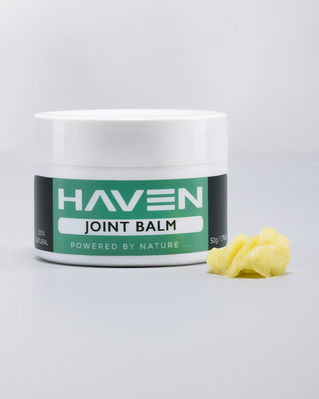 The Haven Joint Balm jar open, with a portion of balm beside it